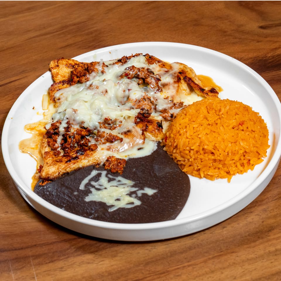 Grilled chicken topped with melted cheese, seasoned meat, orange rice, and refried beans.