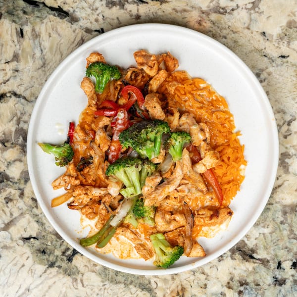 Chicken fajitas with broccoli, bell peppers, onions, and rice on a white plate.